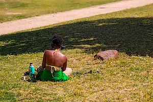 Black woman sitting in sunny urban park from behind, a Person Photo by DanFLCreativo