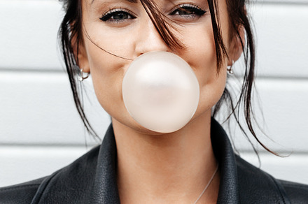 Beautiful young woman blowing a bubble gum balloon