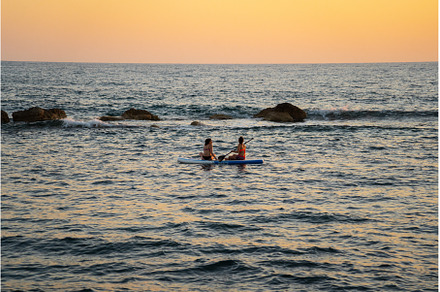 Two women sharing paddle board at, a Person Photo by fotoliza