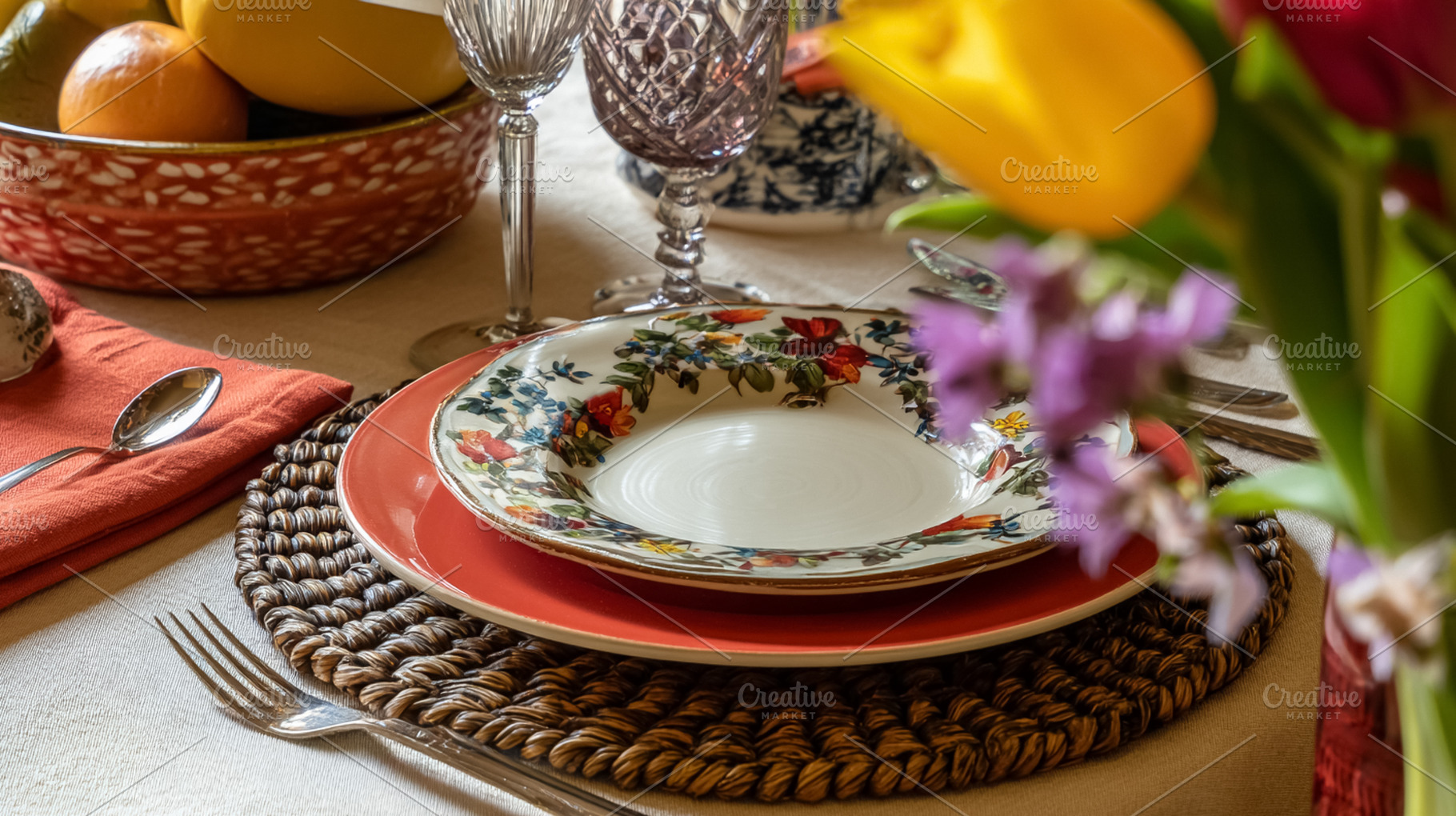 Dining table set with floral patterned plate, elegant glassware,, a Photo by Studio ANNA