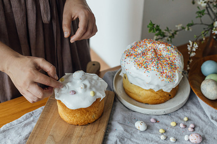 Woman decorating homemade easter bread with sugar glaze and cand, a Holiday Photo by Sonjachni