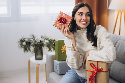 Beautiful happy woman unwrapping New Year or Christmas presents