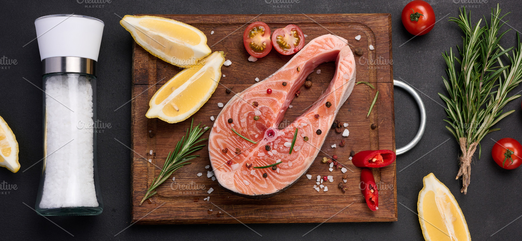 Raw salmon steak on a wooden cutting board, lemon slices, spices, a Food & Drink Photo by ndanko