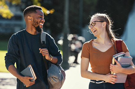 Education, diversity friends and students walking to college lecture class, school campus and talking on fun journey. University study, communication and learning black man and woman happy on travel, a Photo by Peopleimages.com