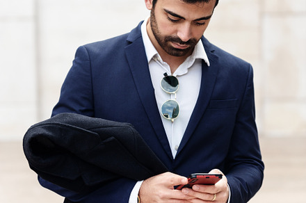 Man in suit looking at his cell phon, a Person Photo by Perpis