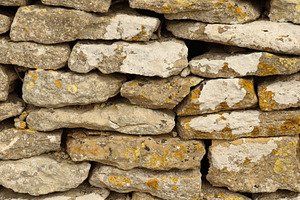 Dry stone walling detail showing rough textured rock surface with various earth, a Photo by Studio ANNA