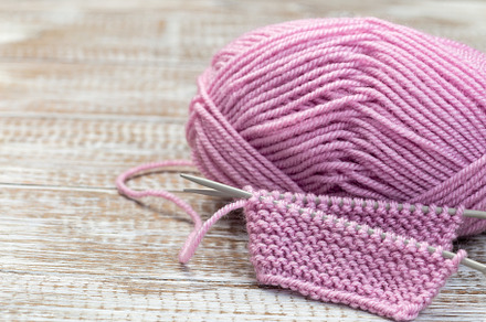 Piece of knitting with needles and pink yarn skein on wooden background, horizo, an Arts & Entertainment Photo by iuliia_n