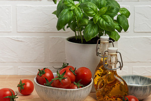 Cherry tomatoes and basil with olive oil on kitchen table, a Food & Drink Photo by Olena Rudo
