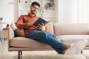 Smiling Arab man in glasses reading paper book, a Photo by Prostock-Studio (Thumbnail 1 of 2)