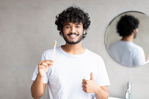 Oral care concept. Happy indian guy holding toothbrush and showing thumb up, po, a Person Photo by Prostock-Studio