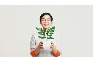 Asian woman holding a potted plant, a Person Photo by Sergey Kotenev