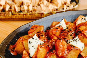 patatas bravas and chipirones on wooden table, a Photo by Nito