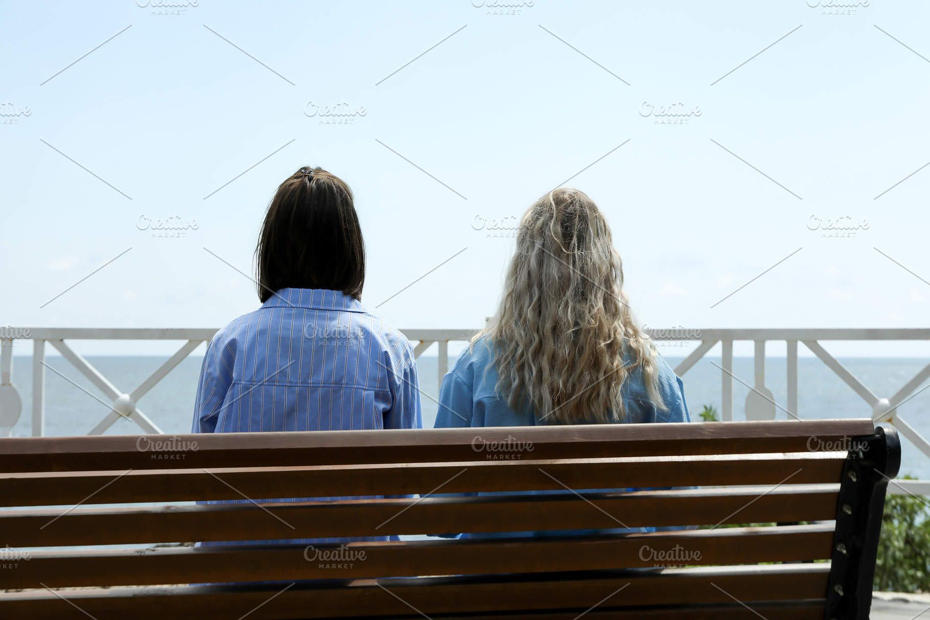 Two young women sitting on bench near sea, a Holiday Photo by AtlasStudio PRO