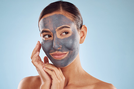 Clay face mask, skincare and woman with beauty in studio isolated on blue background. Cosmetics, model and natural facial treatment for peeling to exfoliate skin, dermatology or cleaning for wellness, a Photo by Peopleimages.com