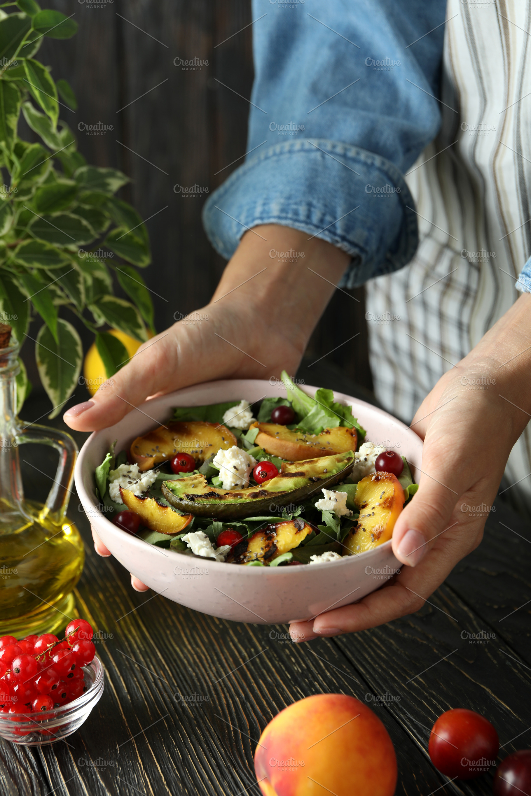 Woman in apron holds plate with salad with grilled peach, a Food & Drink Photo by AtlasStudio PRO