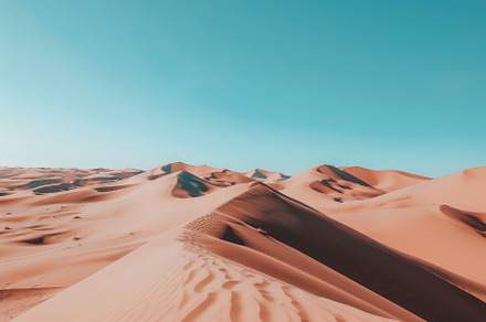 Golden sand dunes stretch across the, a Photo by Tanuart