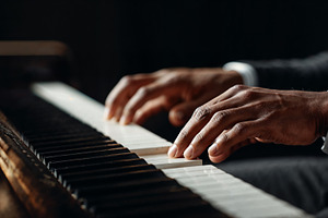 Elegant hands playing piano keys in a dimly lit room, a Person Photo by OSORIOartist