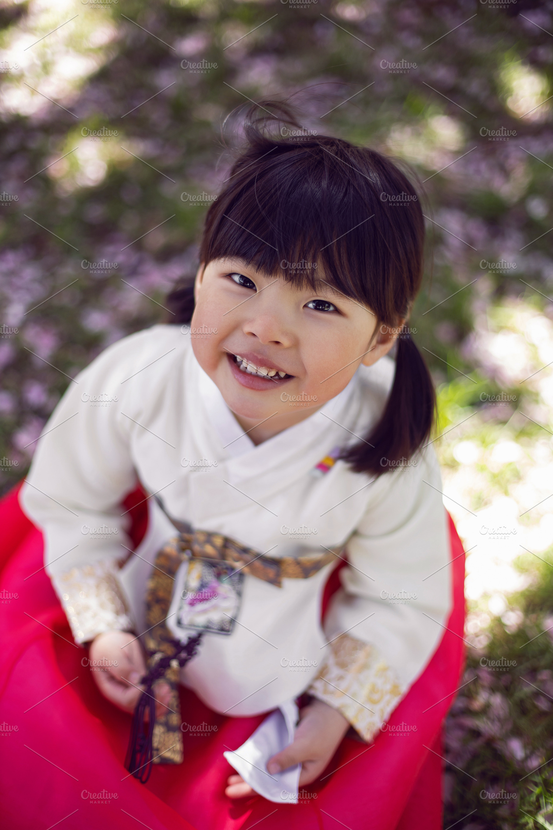 Korean girl child in a national costume walks in a garden with cherry blossoms, a Person Photo by SaulichPhoto
