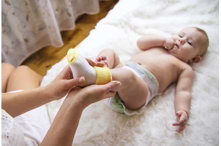 Mother puts socks on the little baby, a Person Photo by yanadjana