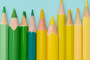 Close-up of a row of green and yellow wooden pencils on a blue b, a School & Education Photo by ndanko