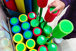 Child selecting colorful pool noodles toys with playful designs on a store shel, a Photo by AS photostudio