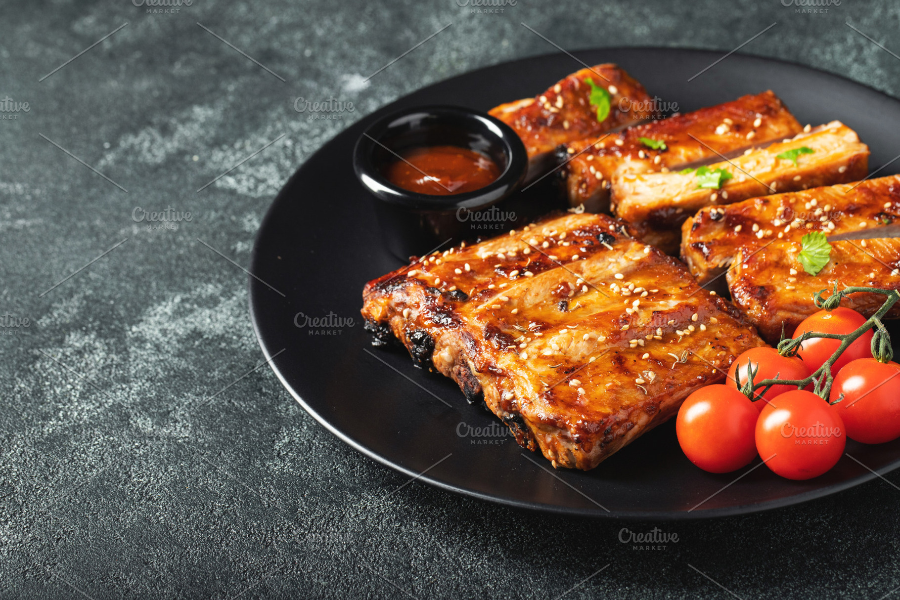 Hot grilled spare ribs from a summer BBQ served on a plate with sauce. Top view, a Food & Drink Photo by Budarinphoto