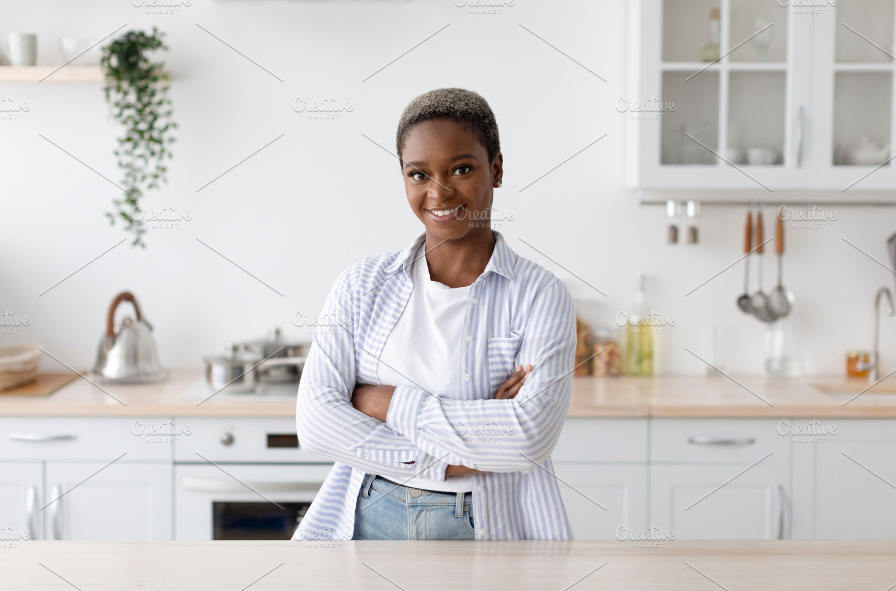 Smiling millennial african american woman in casual with crossed arms looking a, a Person Photo by Prostock-Studio