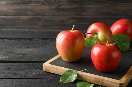 Apples and cutting board on wooden background, space for text, a Food & Drink Photo by AtlasStudio