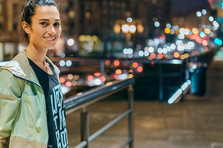 Woman wearing sportswear looking at camera with night town on background, a Sports & Recreation Photo by davidpereiras