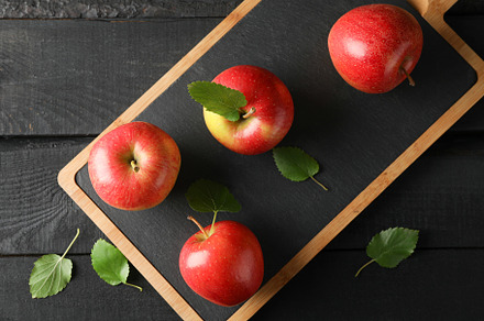Apples and cutting board on wooden background, space for text, a Food & Drink Photo by AtlasStudio