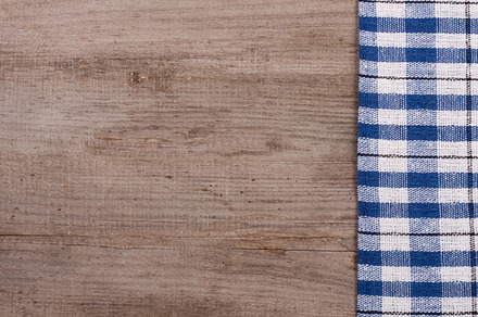Blue checkered tablecloth on an old wooden table with copy space for your, an Abstract Photo by NataPhoto