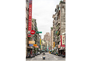 Scooter navigating a sign-lined, an Architecture Photo by Leonid Andronov