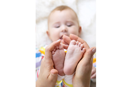The mother holds the legs of her, a Person Photo by yanadjana
