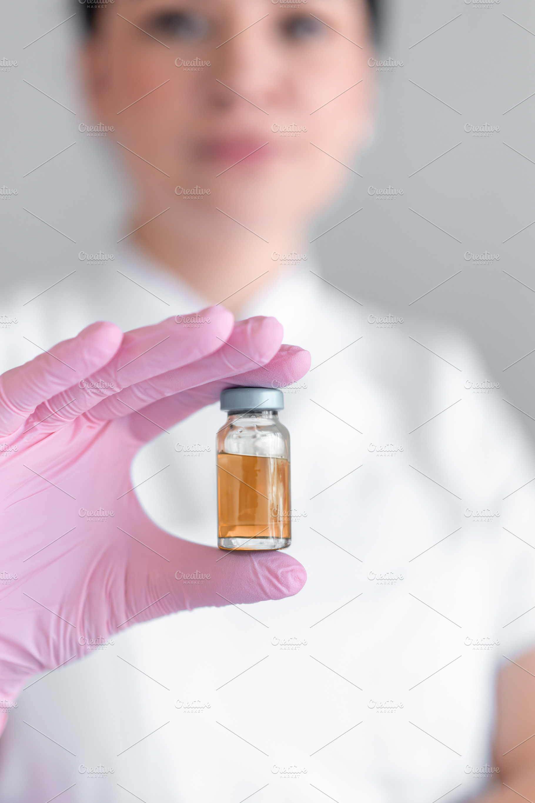 Female cosmetologist holding medicine bottle for injection at clinic, a Photo by andreonegin market