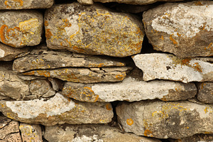 Dry stone wall texture with weathered stones and colorful lichen, natural rusti, a Photo by Studio ANNA