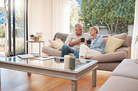 Relax, retirement and coffee with elderly couple bonding on a sofa, enjoying a peaceful morning in their living room together. Love, man and woman enjoying, break, relationship and cozy conversation, a Photo by Peopleimages.com