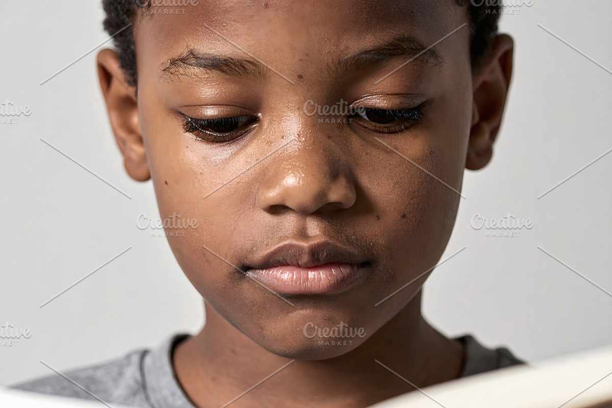 Young boy reading book with calm focused expression, a Person Photo by GoodGoods (Photo 1 of 2)