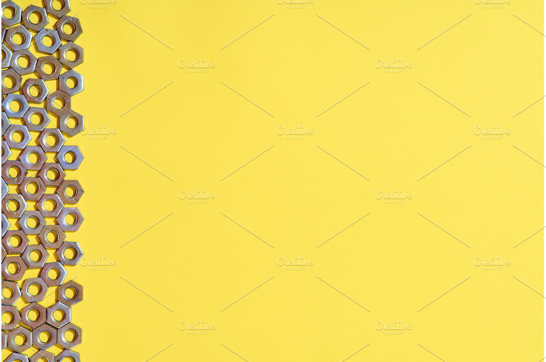 Vertical metal nuts border on yellow, an Industrial Photo by Gladkov photography
