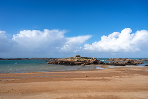 Rocky tidal island under bright skies in Tregastel, Brittany, Fr, a Nature Photo by GoodGoods