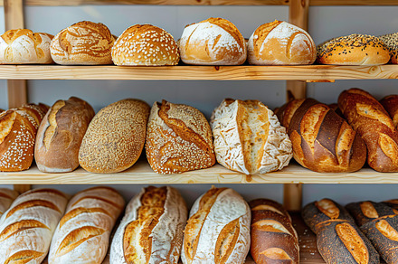 Different kinds of baked bread on shelves in bakery shop, a Food & Drink Photo by AlyaAnd