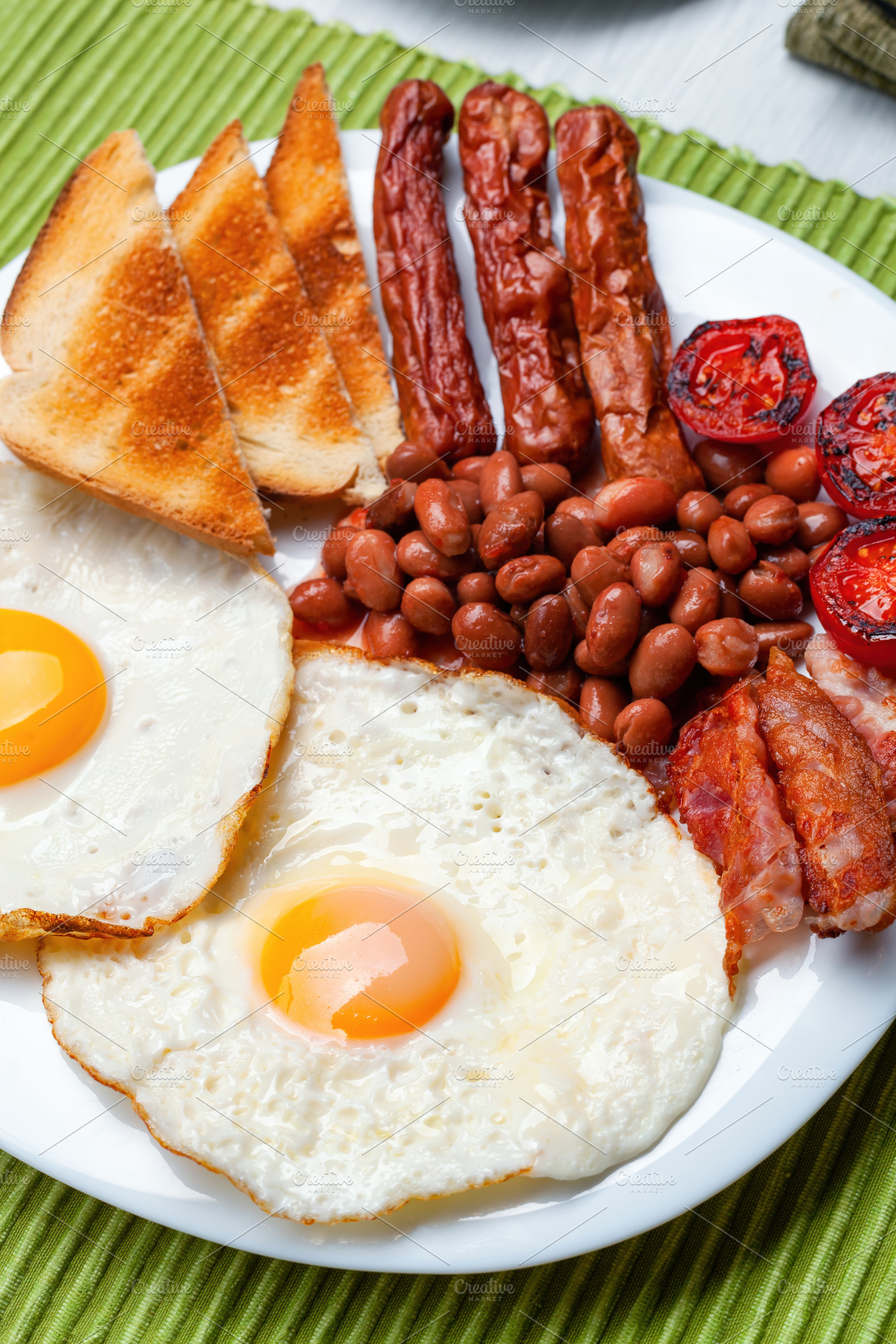 Full English breakfast with fried eggs, sausages, bacon, beans and toasts, a Food & Drink Photo by Antonio Gravante Market