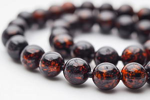 Dark amber stone beads on white, a Background Photo by MistyDay