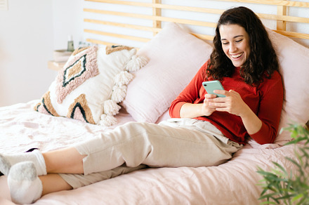 Woman relaxing and having fun with a smartphone on the bed, a Person Photo by asife