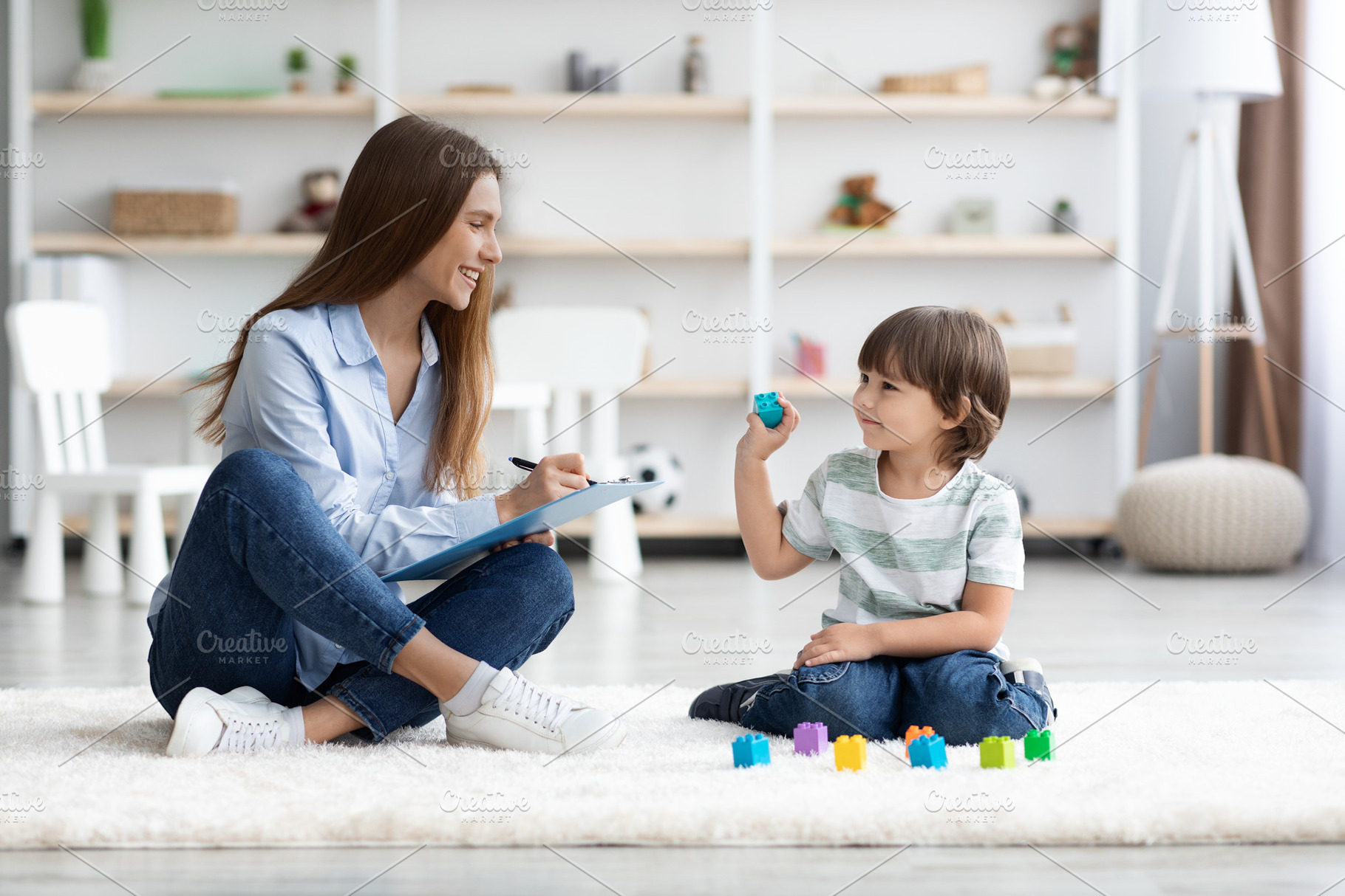Cute little boy playing with colorful blocks, young professional woman psycholo, a Photo by Prostock-Studio