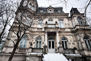 Old mansion in winter snow with grand steps and ornate facade under bare trees, a Photo by AS photostudio
