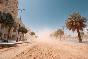 Dust storm sweeps through urban streets during mid-afternoon heat in a city set, a Photo by AlyaAnd