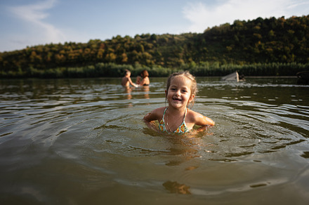 Joyful child swimming in serene river on a sunny day, a Person Photo by AS photostudio