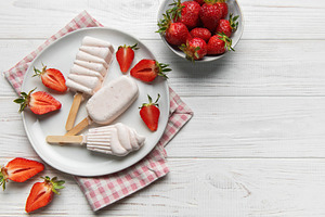 Homemade strawberry ice cream popsicles on white wood, a Food & Drink Photo by Olena Rudo