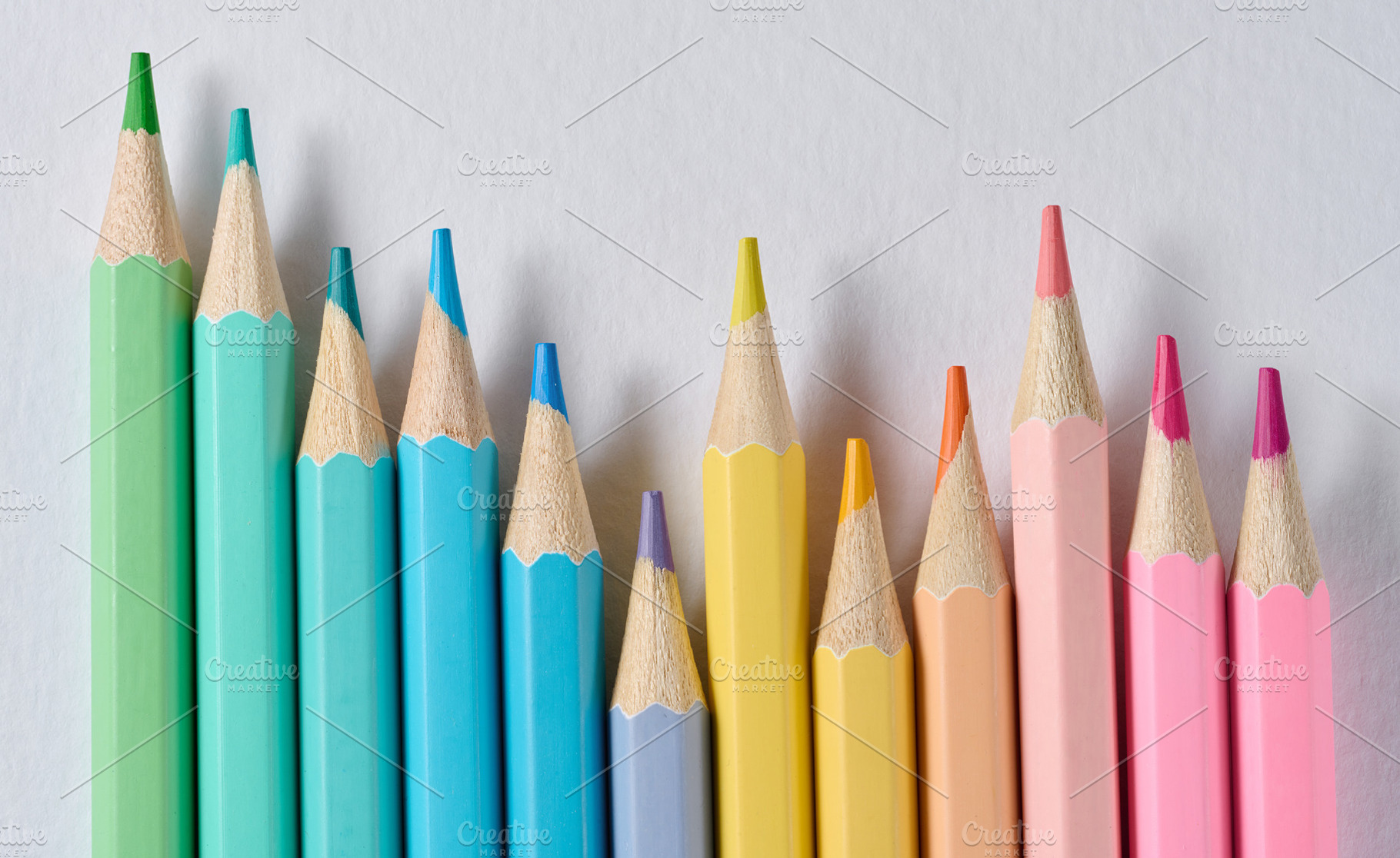 A row of colored wooden pencils with sharp tips on a white backg, an Abstract Photo by ndanko