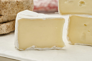 Sliced round head of Camembert cheese on a white board, a Food & Drink Photo by ndanko